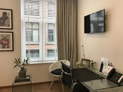 a living room with a desk and a window at Antwerp Business Suites in Antwerp