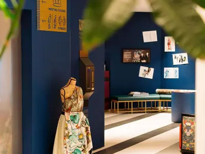 a room with a blue wall with a dress and a bench at Maek Hotel Antwerp Central - Handwritten Collection by Accor in Antwerp