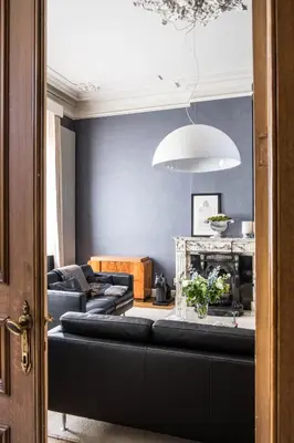 a living room with blue walls and a black couch at B&B Dusk till dawn in Mechelen