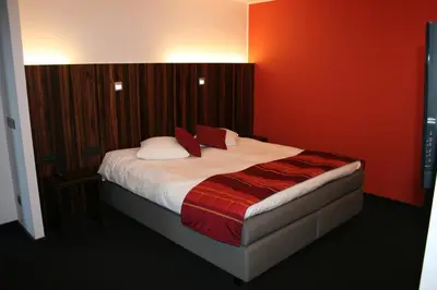 a bedroom with a large bed with red walls at Hotel Carpinus in Leuven
