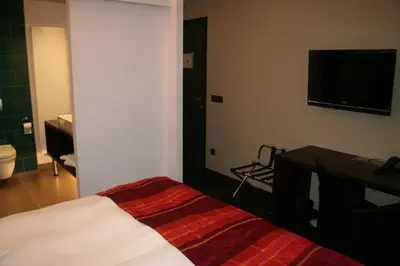 a bedroom with a bed and a desk and a television at Hotel Carpinus in Leuven