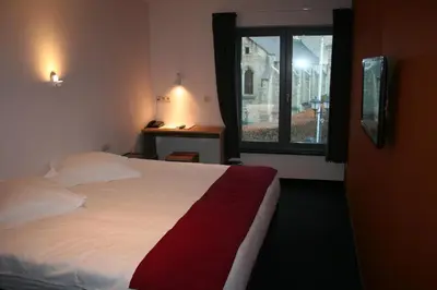 a bedroom with a large bed with a window at Hotel Carpinus in Leuven