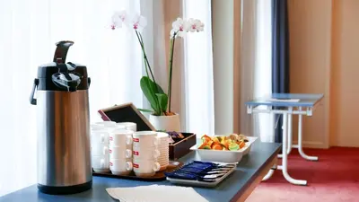a table with a coffee maker and a bowl of fruit at Atlas Hotel Brussels in Brussels