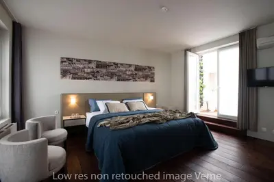 a bedroom with a large bed and a television at Hotel 'T Sandt in Antwerp