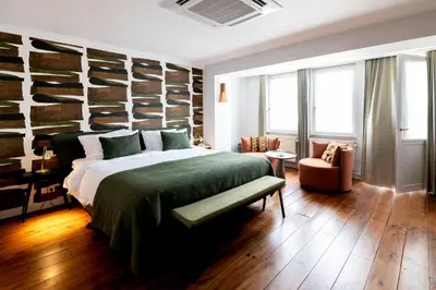 a bedroom with a large bed with a green blanket at Hotel 'T Sandt in Antwerp