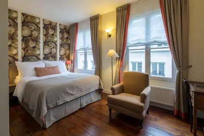 a bedroom with a bed and a chair and windows at Hotel 'T Sandt in Antwerp