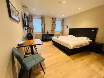 a bedroom with a bed and a desk and a table at Parkhotel Gent Centrum in Ghent