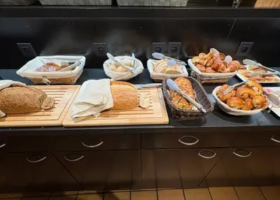 a counter with many different types of bread and pastries at Parkhotel Gent Centrum in Ghent