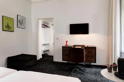 a bedroom with a desk and a chair and a television at Vintage Hotel Brussels in Brussels