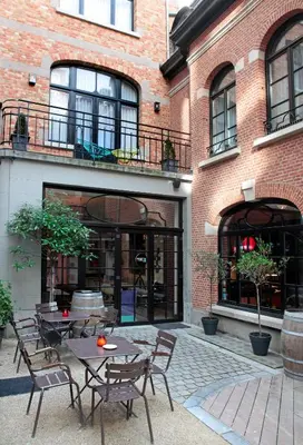 a patio with tables and chairs in front of a brick building at Vintage Hotel Brussels in Brussels