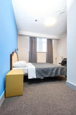 a bedroom with a large bed with a blue wall at Hotel Derby MERODE in Brussels