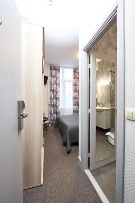 a room with a bed and a bathroom with a mirror at Hotel Derby MERODE in Brussels