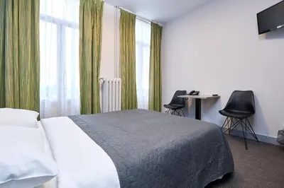 a bedroom with a bed and two chairs and a desk at Hotel Derby MERODE in Brussels