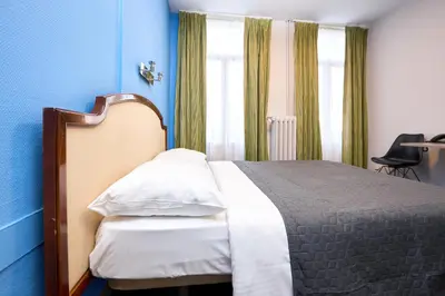 a bedroom with a bed with blue walls and a window at Hotel Derby MERODE in Brussels