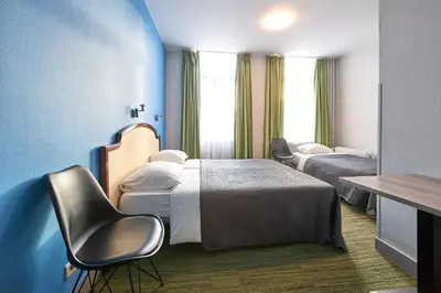 a hotel room with two beds and a chair at Hotel Derby MERODE in Brussels