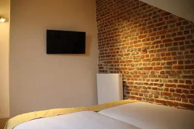 a bedroom with a brick wall with a bed and a television at Hostellerie De Biek in Moorsel