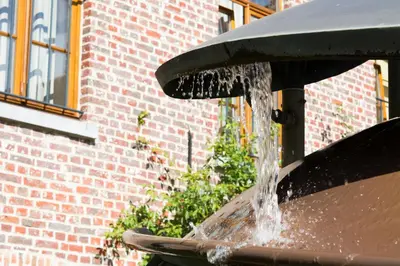 a water fountain in front of a brick building at Hostellerie De Biek in Moorsel