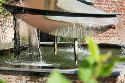 a water fountain in front of a brick building at Hostellerie De Biek in Moorsel