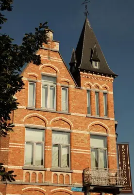 a tall brick building with a black roof at Boardhousing in Leuven
