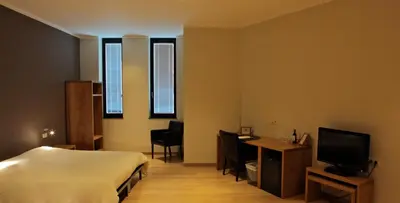 a hotel room with a bed and a desk and a television at Boardhousing in Leuven