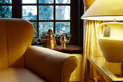 a room with a chair and a lamp and a window at Hotel Ter Driezen in Turnhout