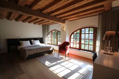 a bedroom with a bed and a chair and windows at B&B Baron’s House Neerijse-Leuven in Neerijse