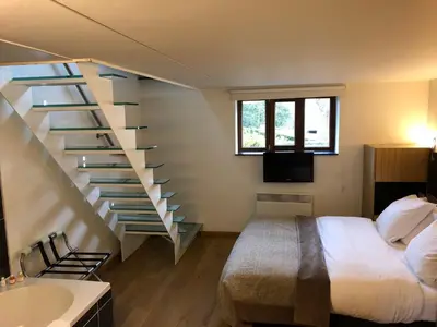 a bedroom with a staircase next to a bed and a sink at B&B Baron’s House Neerijse-Leuven in Neerijse