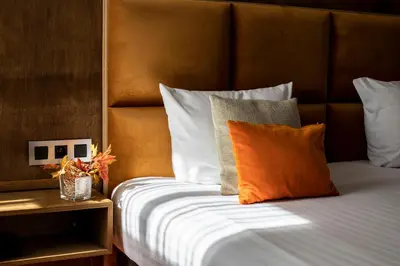a bed with an orange pillow on top of it at Hotel Esperance in Brussels