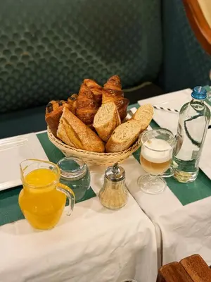 a table with a basket of bread and glasses of beer at Hotel Esperance in Brussels