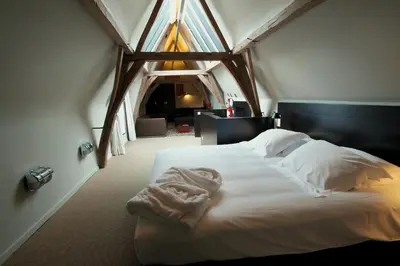 a bedroom with a bed with white sheets and a window at Hotel Matelote in Antwerp
