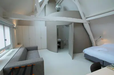 a bedroom with a bed and a couch in a room at Hotel Matelote in Antwerp