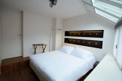 a bedroom with a large white bed and a window at Hotel Matelote in Antwerp