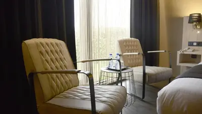 a room with two chairs and a bed and a window at Van der Valk Hotel Beveren in Beveren