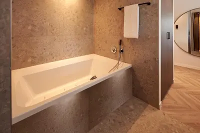 a bathroom with a bath tub in the corner at Van der Valk Hotel Beveren in Beveren