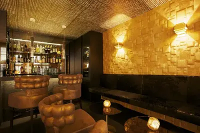 a bar with brown leather stools and a bar at Hotel De Witte Lelie -Small Luxury Hotels of the World in Antwerp