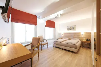 a bedroom with a bed and a desk and chairs at Hotel Royal Astrid in Aalst