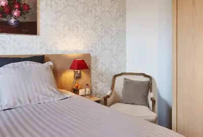 a bedroom with a bed and a chair and a lamp at Hotel Royal Astrid in Aalst