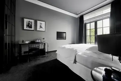 a bedroom with a bed and a desk and a window at Hotel Odette en Ville in Brussels
