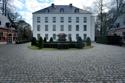 a large white building with a courtyard in front of it at Hotel Kasteel Solhof in Aartselaar