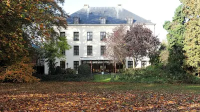 a large white house with trees and leaves in front of it at Hotel Kasteel Solhof in Aartselaar