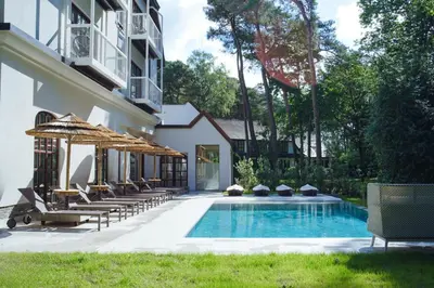 a swimming pool with chairs and umbrellas next to a building at Corsendonk Hooge Heyde in Lichtaart