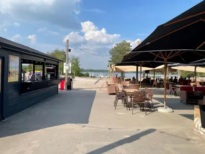 a patio with tables and chairs and umbrellas on the beach at Sunparks Kempense Meren in Mol