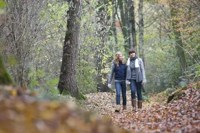 a man and a woman walking down a trail in the woods at Sunparks Kempense Meren in Mol