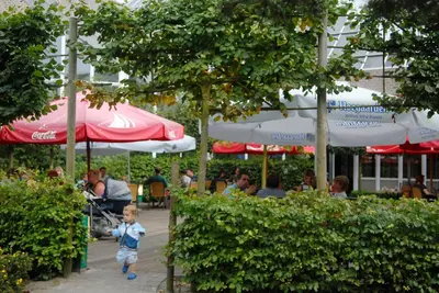 a little boy walking down a sidewalk in front of a restaurant at Sunparks Kempense Meren in Mol