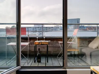 a table and chairs on a balcony with a bottle of wine at Edville Studio in Ghent