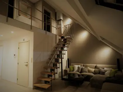 a living room with a couch and a spiral staircase at Villa Einstein Apartments in Antwerp