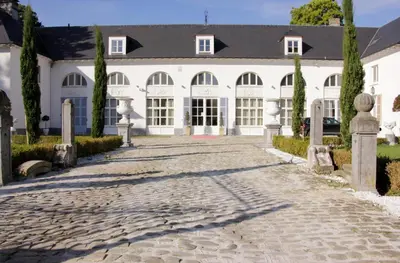 a large white building with a cobblestone driveway at Luxury Suites Arendshof in Antwerp