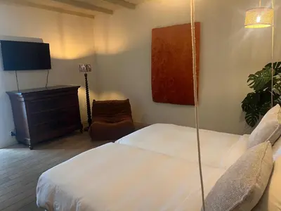 a bedroom with a bed and a chair and a tv at B&B Maryline in Antwerp