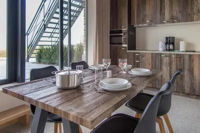 a wooden table with chairs and plates and wine glasses at Eyndevelde in Herzele