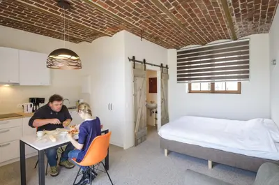a man and woman sitting at a table in a room with a bed at Eyndevelde in Herzele